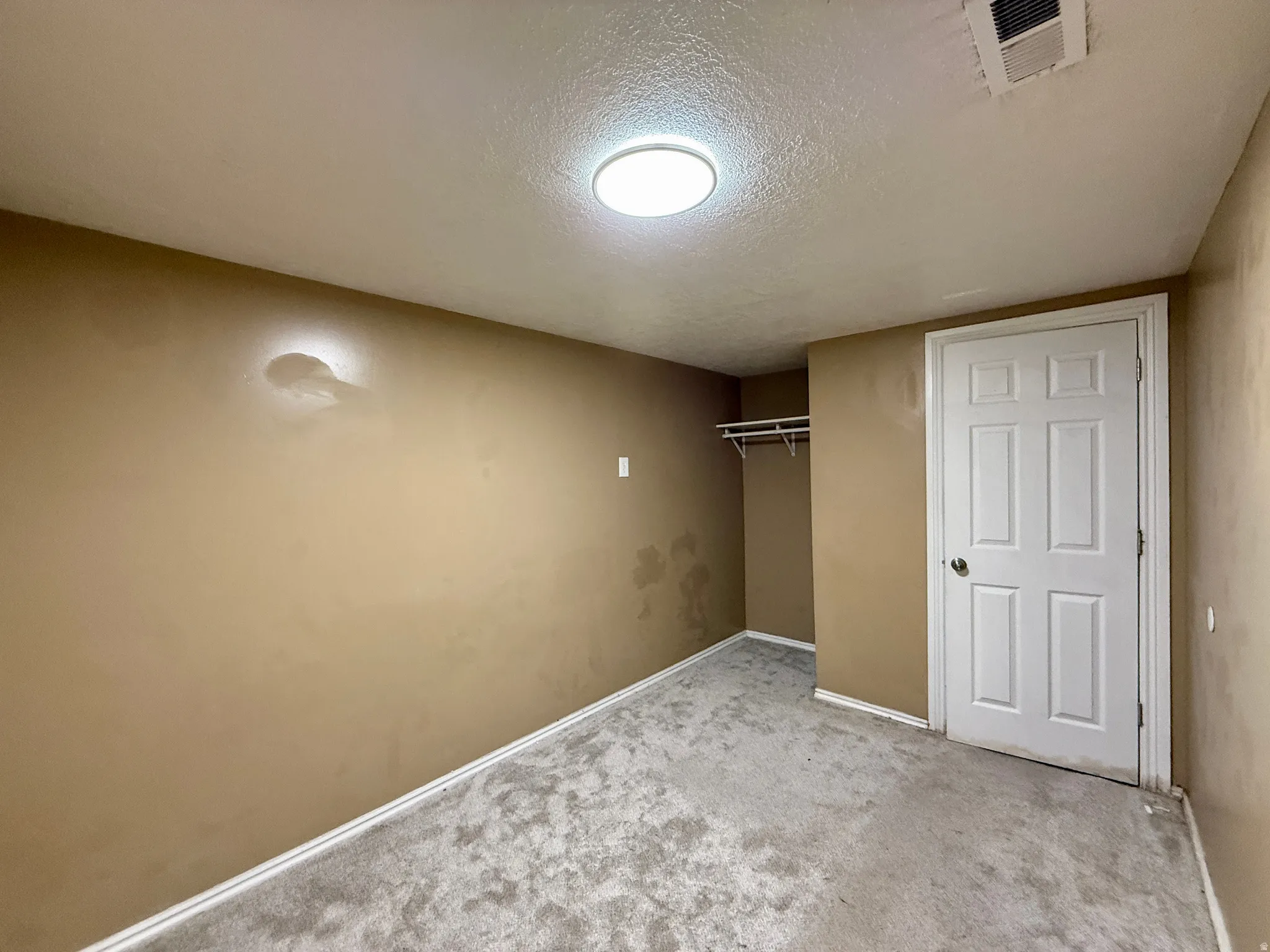 Spacious bedroom with neutral carpeting, recessed ceiling lighting, and a full closet with white six-panel door