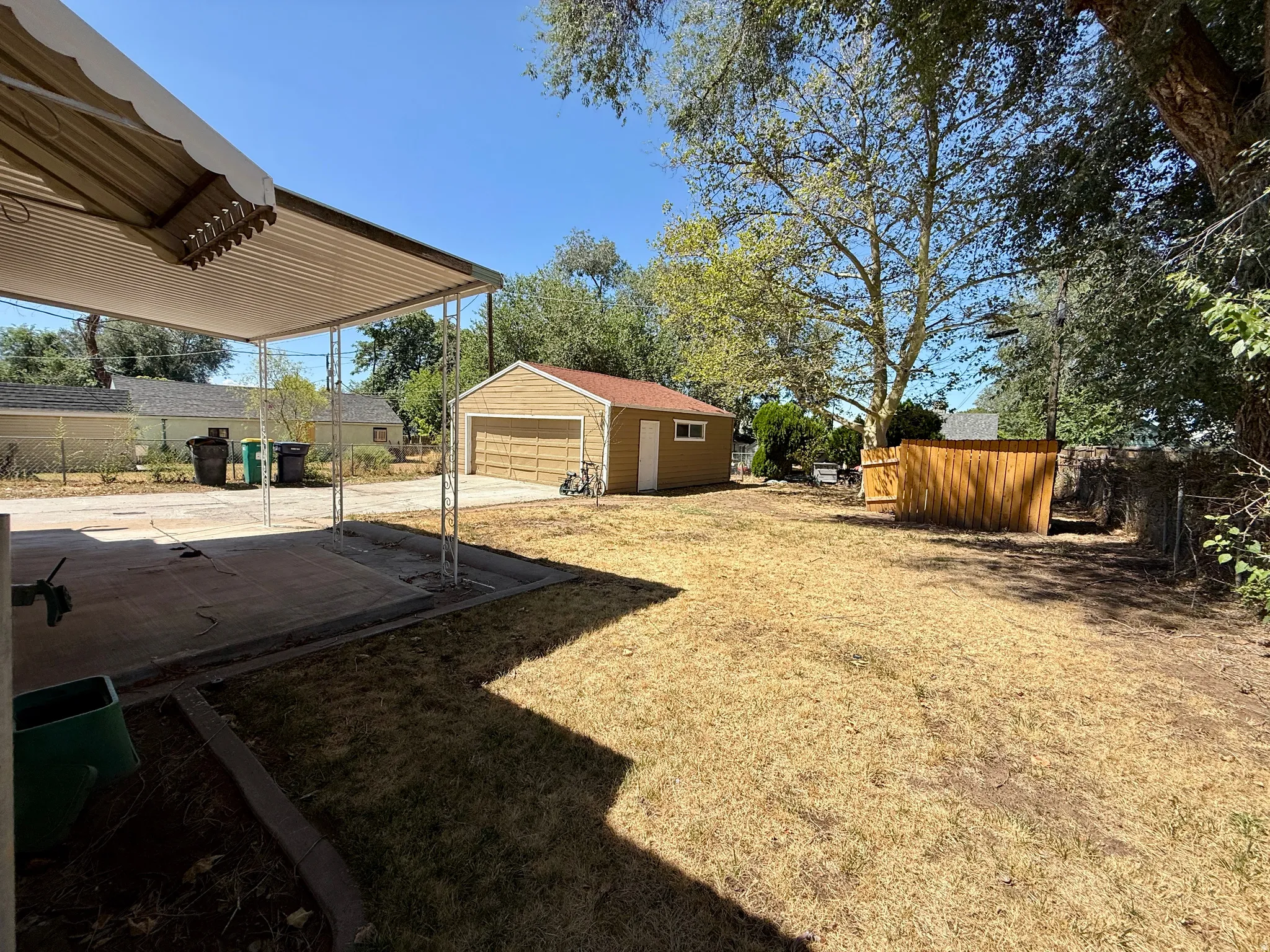 Covered patio with concrete flooring, detached garage, and wood privacy fencing
