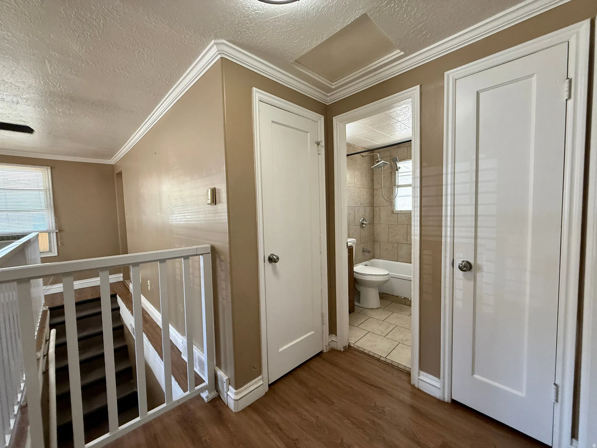 Wood-finish flooring throughout, crown molding detail, and white interior doors