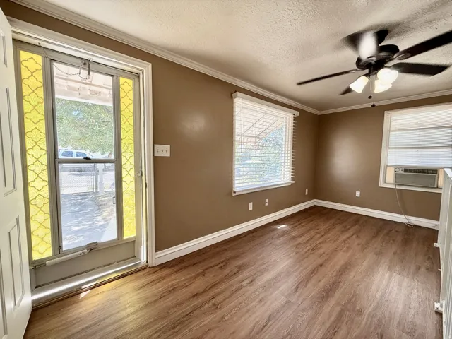 Wood-finish flooring, ceiling fan with light fixture, window blinds, and crown molding