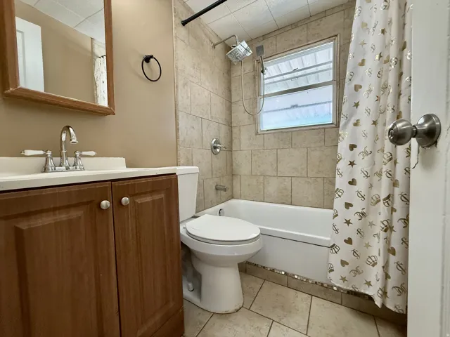 Wood-finish vanity with a white countertop and chrome faucet