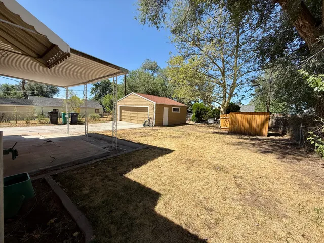 Covered patio with concrete flooring, detached garage, and wood privacy fencing