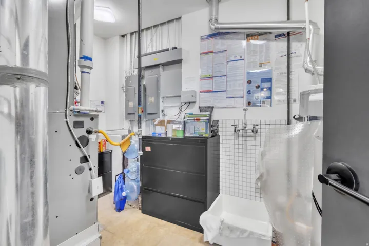 Utility room featuring a built-in wash basin with tile backsplash and exposed ductwork