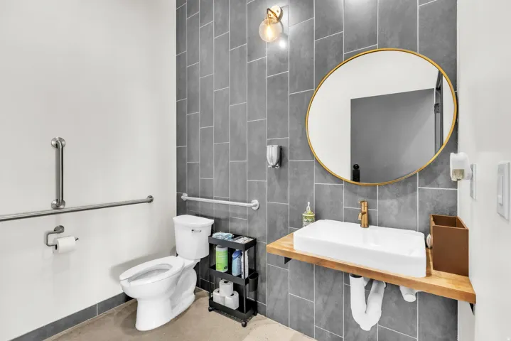 White rectangular vessel sink with a gold-finish faucet, set on a natural wood-finish floating vanity