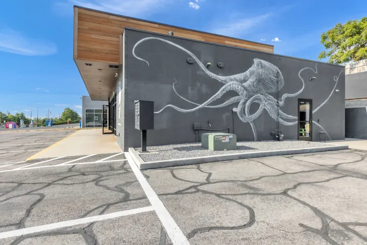 Exterior featuring a large-scale mural, wood-finish soffit, dark-framed entrance, and gravel landscaping
