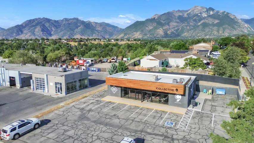 Commercial property featuring a large parking area, two distinct buildings, and a mountainous backdrop
