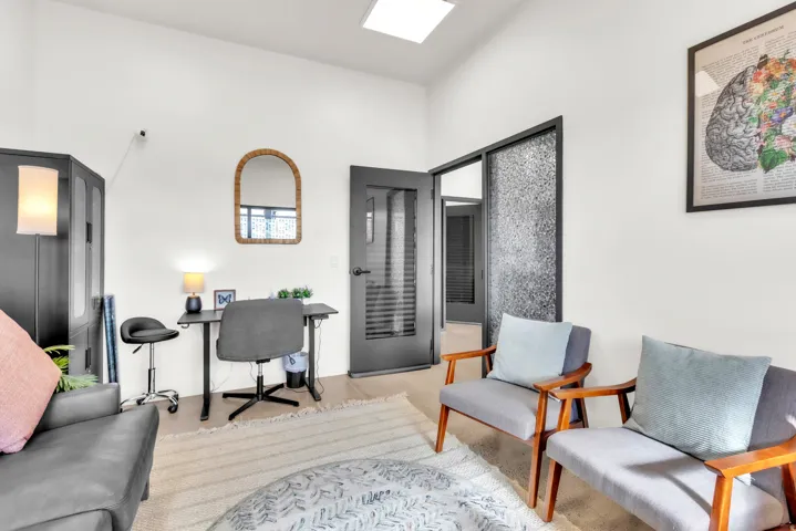 White walls with recessed lighting, skylight, wood-finish flooring, and a dark-paneled door with horizontal window inserts