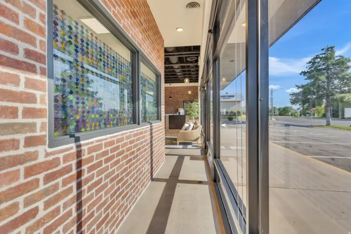 Brick exterior with large windows, covered outdoor walkway, and recessed lighting