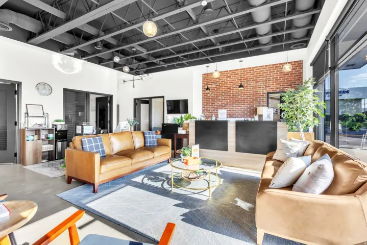 Exposed brick accent wall, high exposed ceiling, concrete flooring, dual reception desk, and large exterior windows