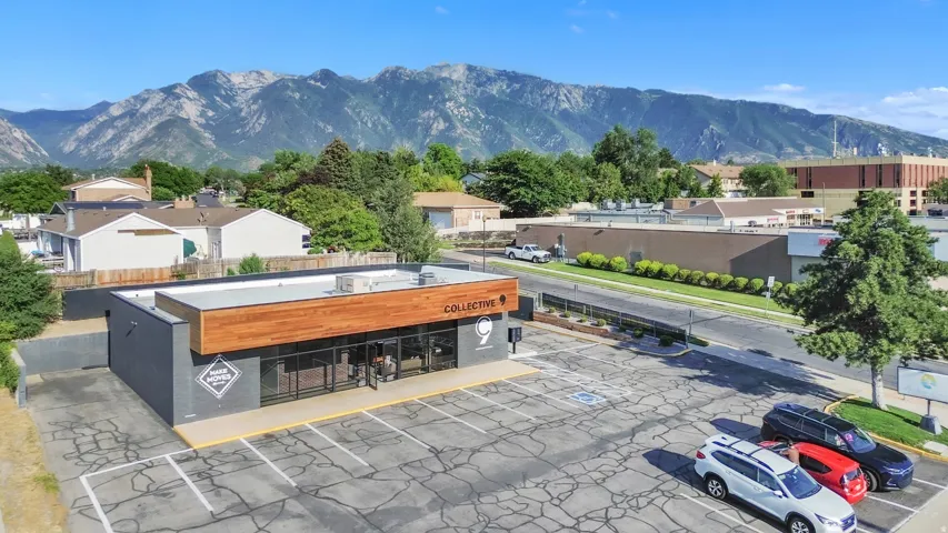 Contemporary commercial building with a wood-finish facade accent, extensive storefront windows, and an expansive paved parking area