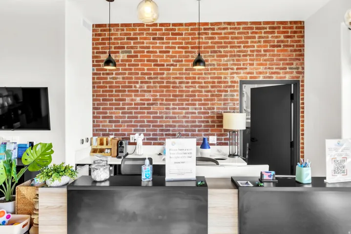 Exposed brick accent wall, pendant lighting fixtures, white countertop surfaces, built-in shelving, and dark paneling