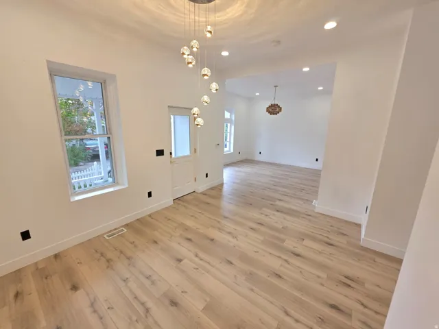 Recessed lighting, wood-finish flooring, and a modern chandelier