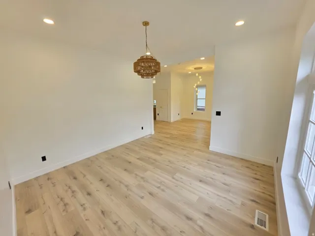 Recessed ceiling lighting, wood-finish flooring, and a decorative pendant light fixture