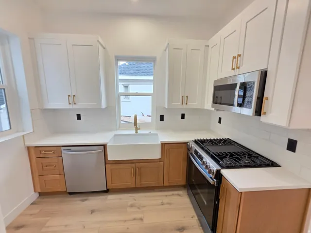 Kitchen featuring white shaker cabinetry, wood-finish lower cabinetry, white subway tile backsplash, white countertops, and stainless steel appliances