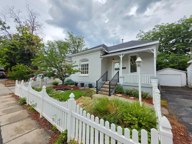 Traditional exterior with a welcoming front porch, a white picket fence, mature landscaping, and a detached garage