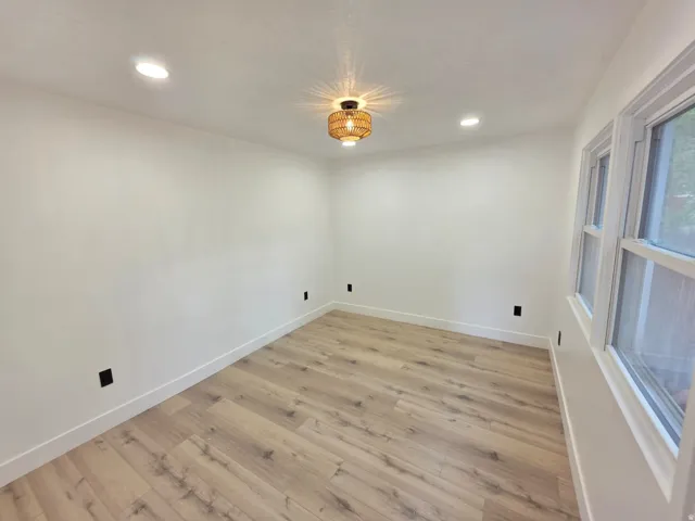 Wood-finish flooring, recessed lighting, and a decorative flush-mount light fixture
