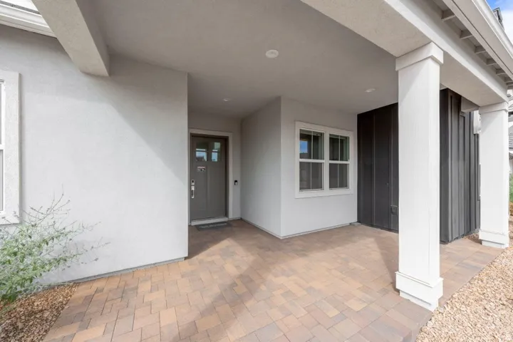 Covered entry with pavers, white columns, and stucco exterior
