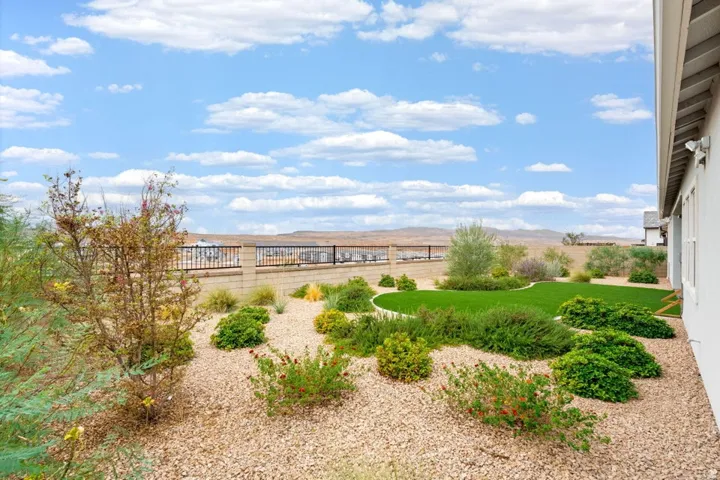 Landscaped backyard featuring artificial turf, gravel ground cover, and planted shrubs