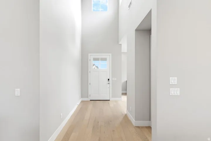 Double-height foyer with a transom window, wood-finish flooring, and white trim