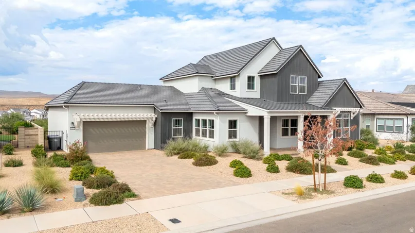 Contemporary exterior with a covered entry, pitched rooflines, attached garage, and paver driveway