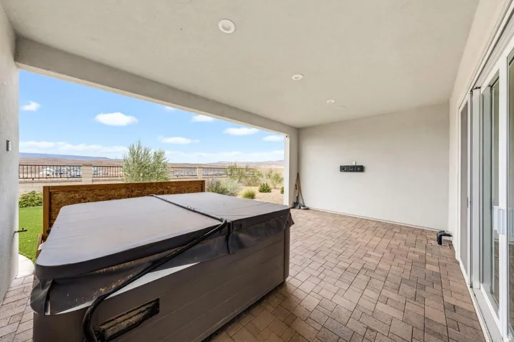 Covered patio featuring paver flooring, built-in recessed lighting, and expansive desert landscaping