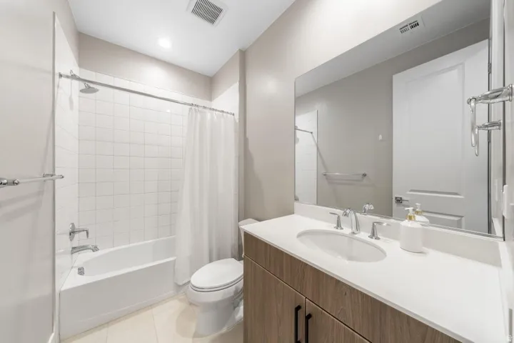 Bathroom featuring a single vanity with wood-finish cabinetry, a white countertop, and a large mirror