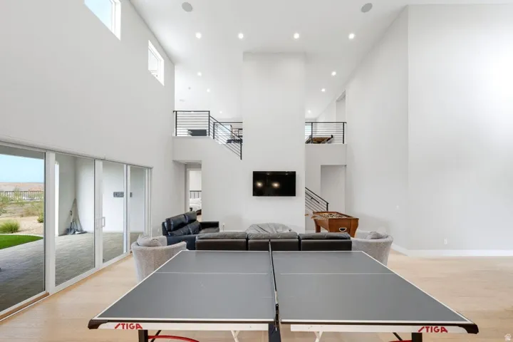 Two-story living area with high ceilings, recessed lighting, wood-finish flooring, and sliding glass doors to the exterior