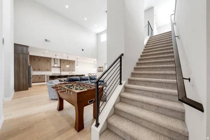 Open-concept living area with vaulted ceilings, light wood-finish flooring, and a kitchen featuring wood cabinetry, an island, and pendant lighting