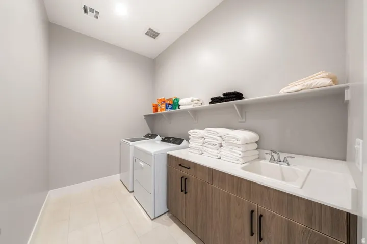 Laundry room featuring a utility sink, wood-finish cabinetry, white countertop, and tiled flooring