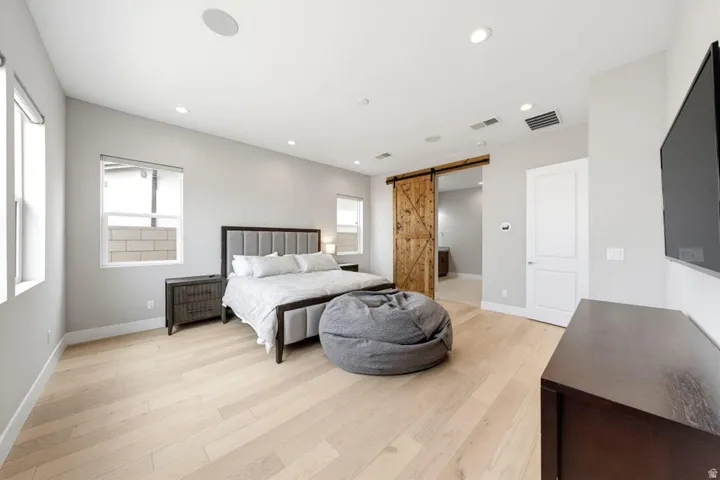 Light wood-finish flooring with recessed lighting and a rustic wood barn door