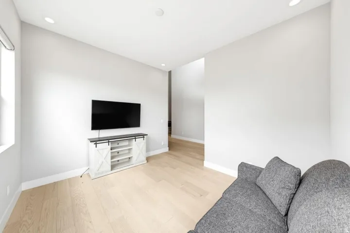 Recessed lighting, light wood-finish flooring, white walls, and a window providing natural light