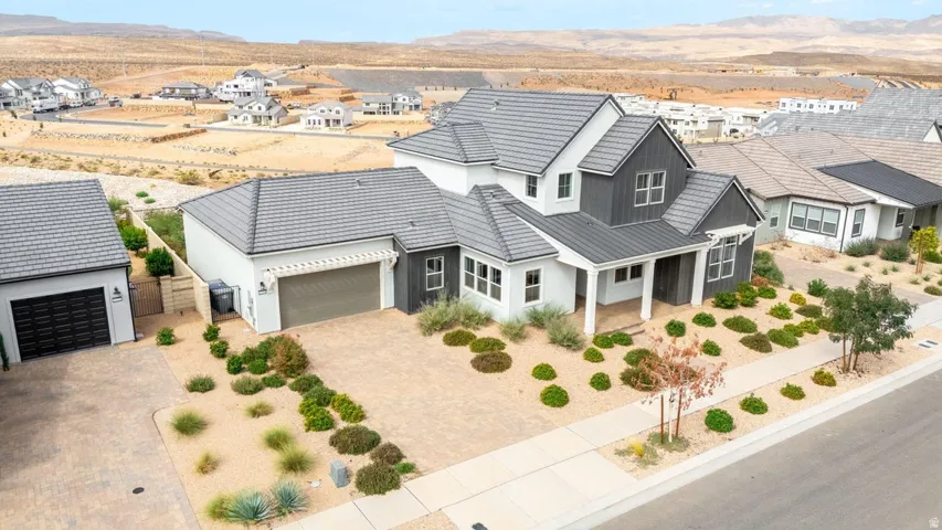 Contemporary exterior with a covered porch, dark gray siding accents, and a light-colored stucco finish