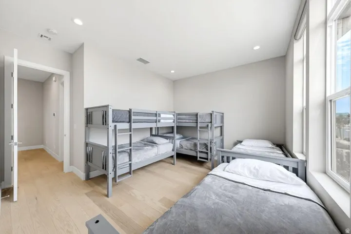 Vaulted ceilings, recessed lighting, light wood-finish flooring, and tall windows