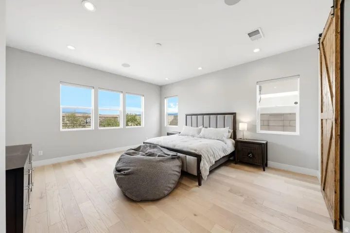 Recessed lighting, wood-finish flooring, multiple windows, and a barn-style sliding door