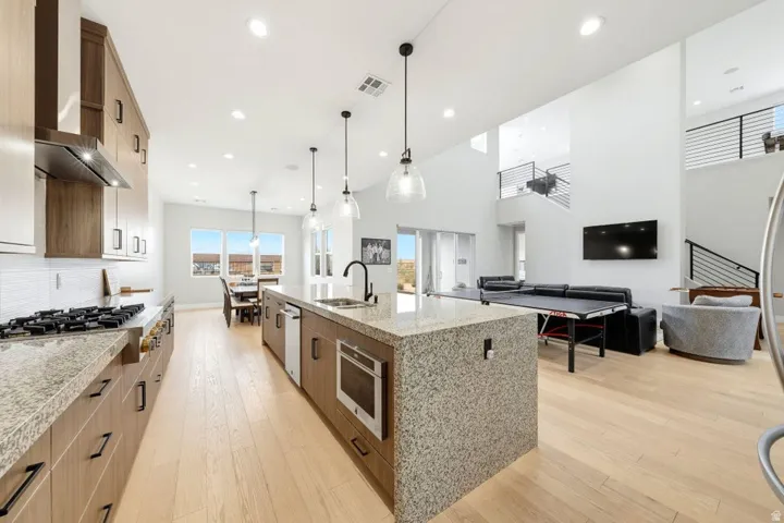 Open-concept living space with a kitchen island, light wood-finish flooring, and high ceilings