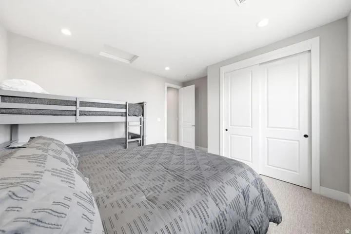 Recessed lighting, light-toned carpeting, panel doors with matte black hardware, and a skylight