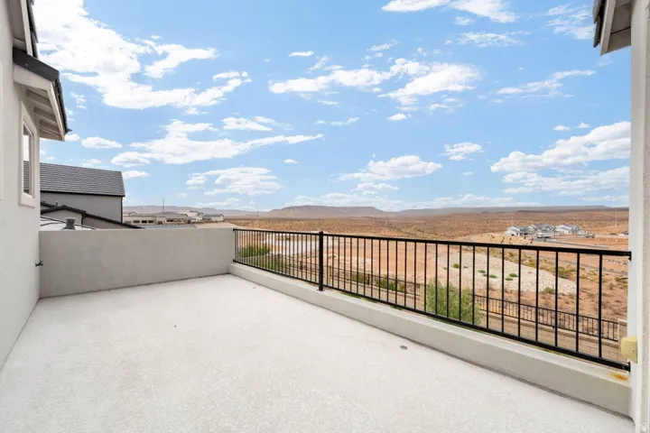 Spacious outdoor balcony with a light-colored concrete surface, featuring a black metal railing
