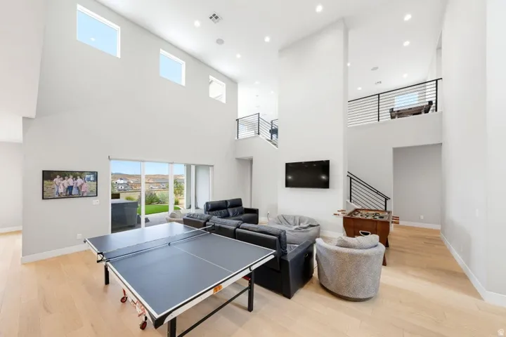 Spacious open-concept living area featuring a vaulted ceiling, recessed lighting, wood-finish flooring, and a sliding glass door