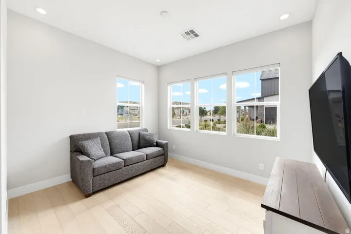 Bright interior space featuring three large windows, recessed ceiling lighting, and wood-finish flooring