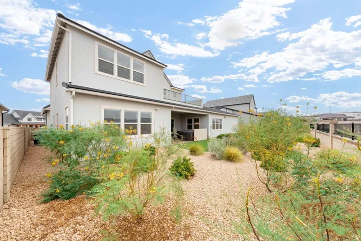Stucco exterior residence with multiple windows, an upper-level balcony, and a lower-level covered patio
