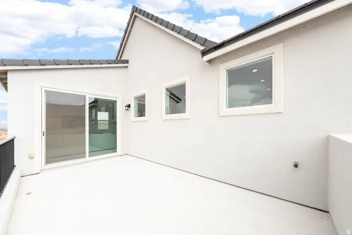 Exterior balcony featuring sliding glass door access, contemporary black railing, and stucco siding