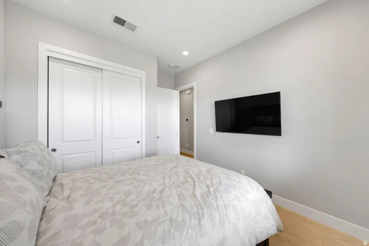 Recessed lighting illuminates wood-finish flooring and a white sliding closet door