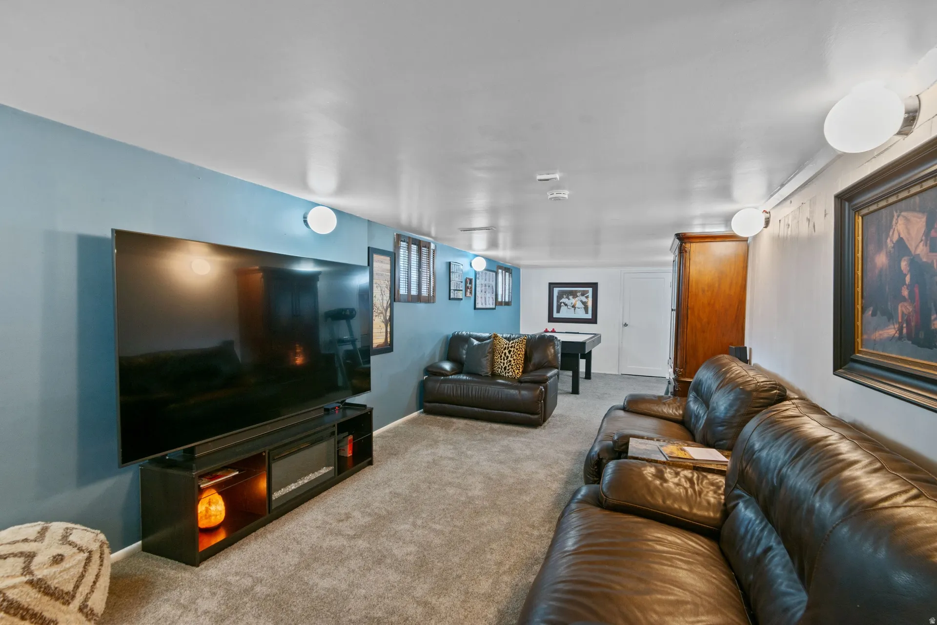 Carpeted flooring, recessed wall lighting, built-in media console, and a contrasting accent wall
