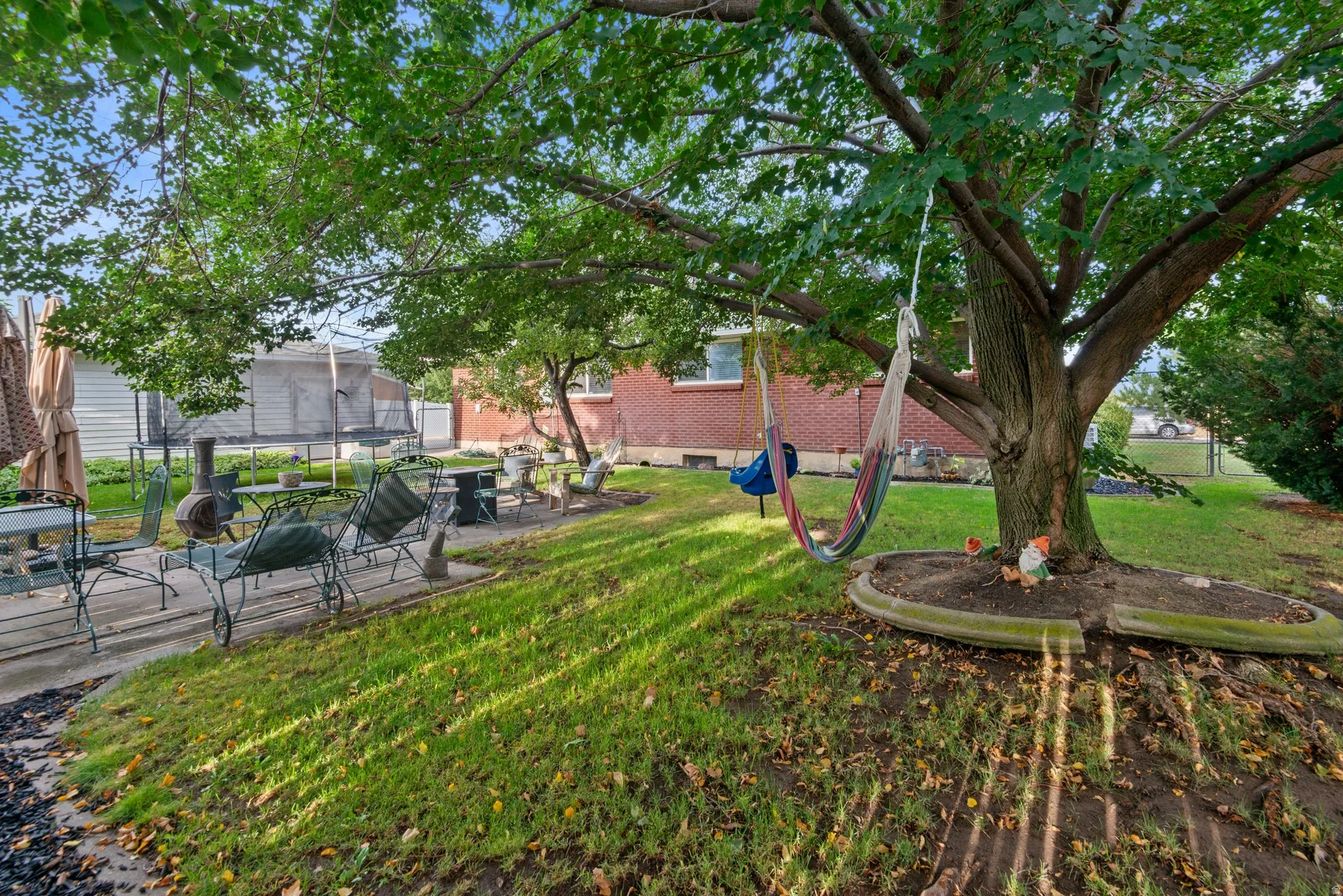 Expansive backyard featuring mature trees, a concrete patio, and a grass lawn