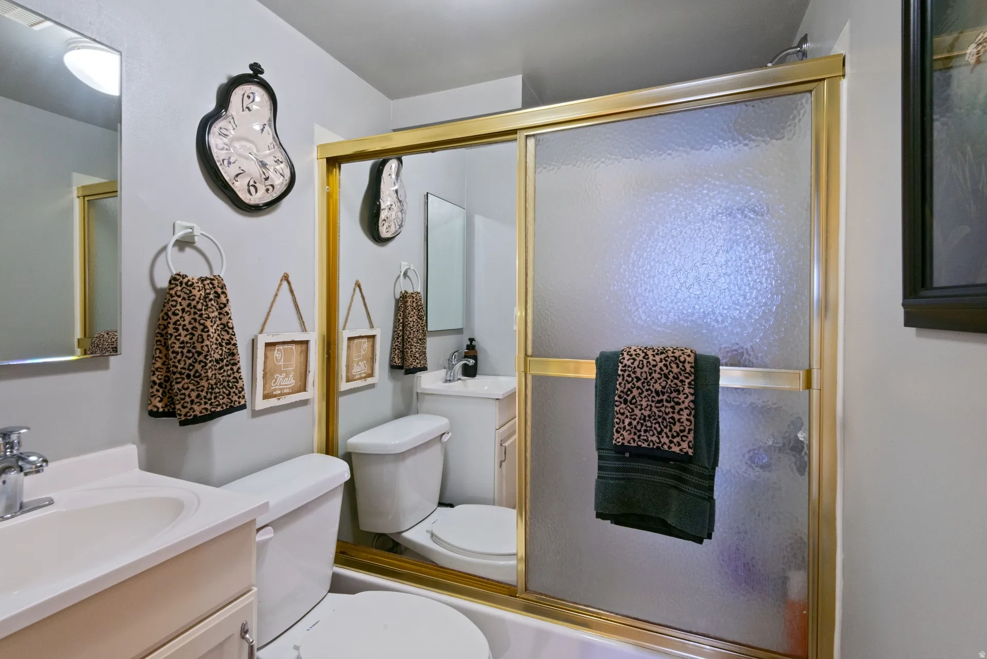 Bathroom with an integrated bathtub and shower featuring a gold-toned framed glass enclosure