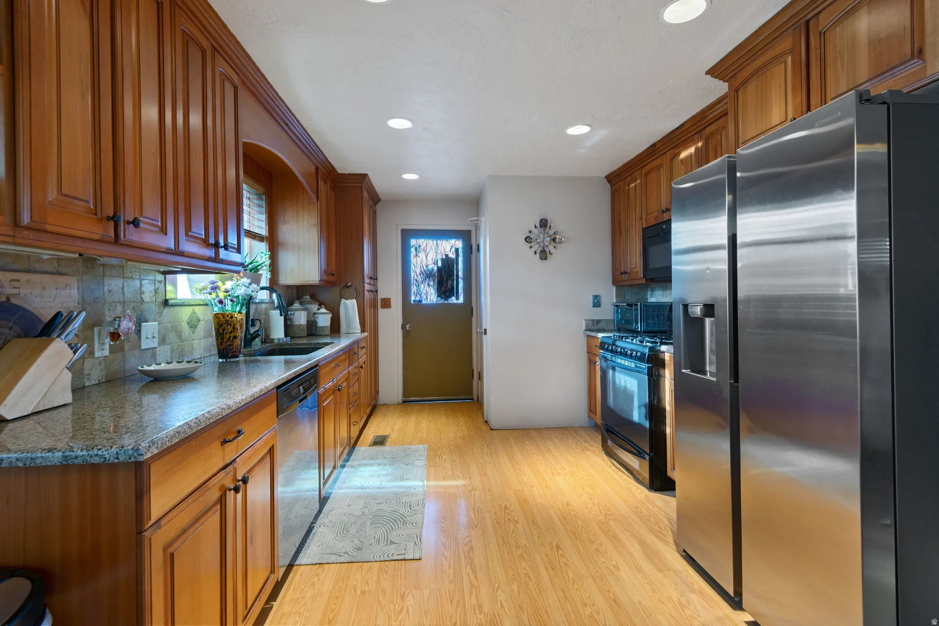 Kitchen featuring wood-finish cabinetry, stainless steel appliances, granite countertops, and a tile backsplash