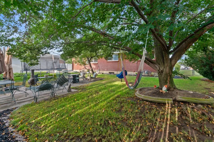 Expansive backyard featuring mature trees, a concrete patio, and a grass lawn