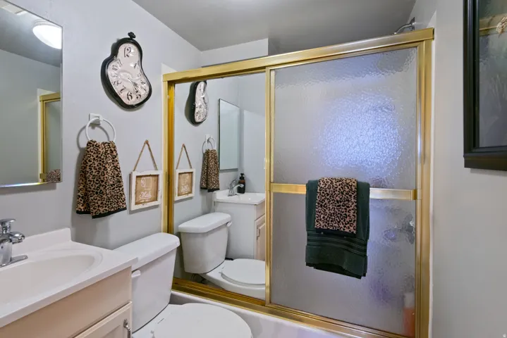 Bathroom with an integrated bathtub and shower featuring a gold-toned framed glass enclosure