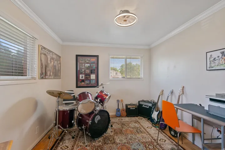 Crown molding, dual windows with blinds, wood-finish flooring, and a flush-mount ceiling light