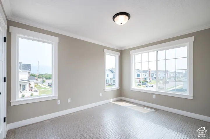 Soft neutral wall color, crown molding, multiple windows, textured carpet flooring, and a semi-flush mount ceiling light